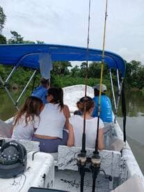 A group enjoys a fishing trip on a boat, surrounded by lush greenery along the river — perfect for family adventures and outdoor experiences.