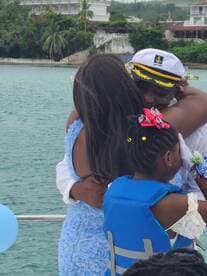 A heartfelt moment as a couple embraces on a boat, surrounded by family, celebrating a special occasion with joy and love.