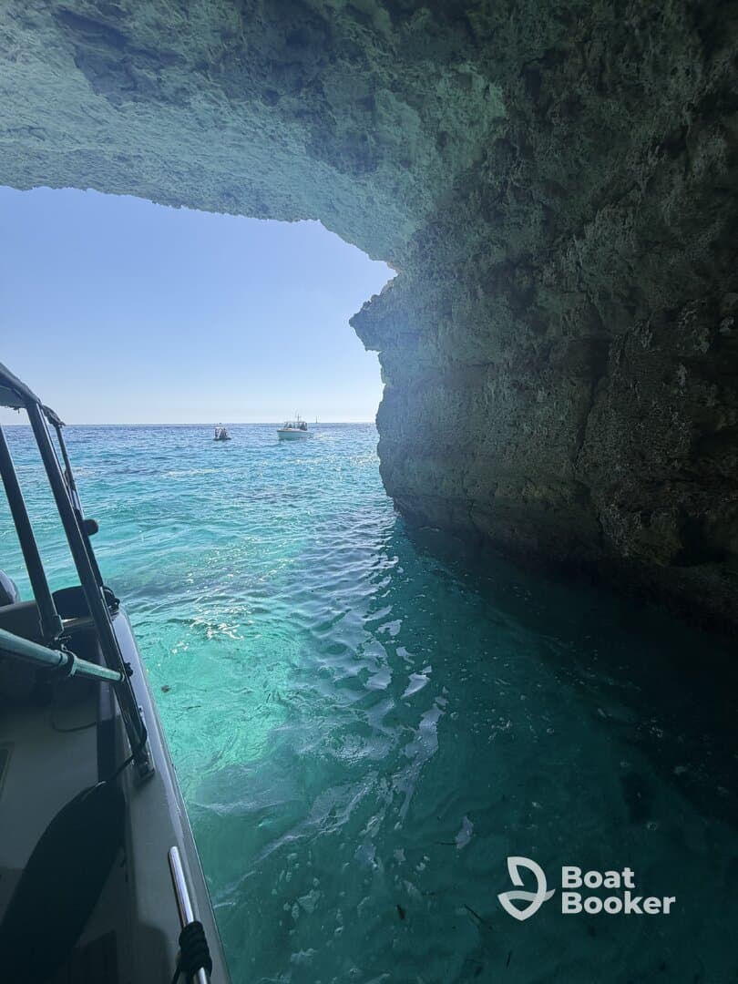 A stunning view from inside a boat looking out at a beautiful cave and turquoise waters, showcasing the natural beauty of the coastline.