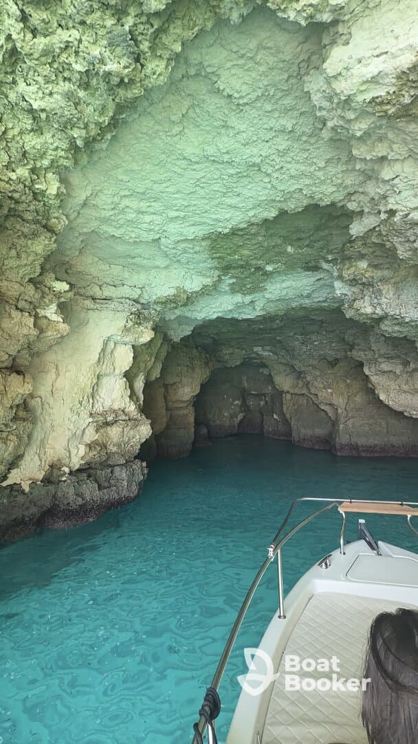 A stunning view of a boat entering a picturesque cave with vibrant turquoise waters, perfect for exploring hidden gems during a boating adventure.