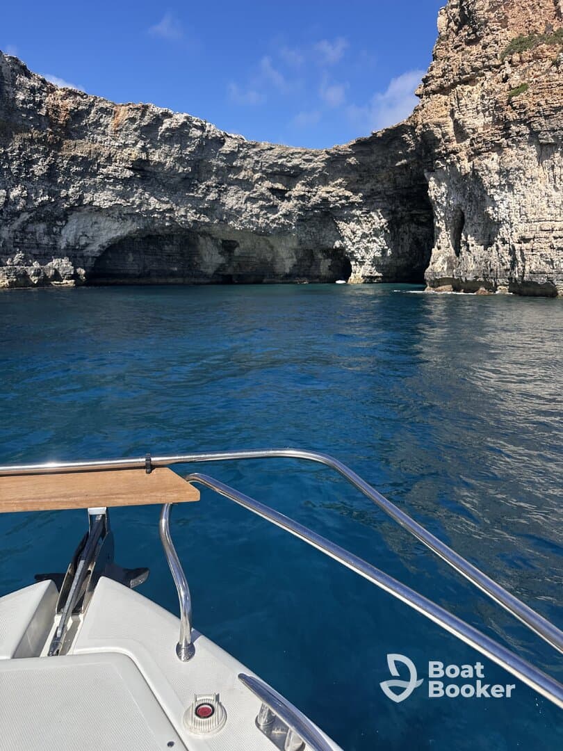 A stunning view of a rocky coastline from the bow of a boat, showcasing the beautiful blue waters and natural formations — perfect for exploring scenic destinations.