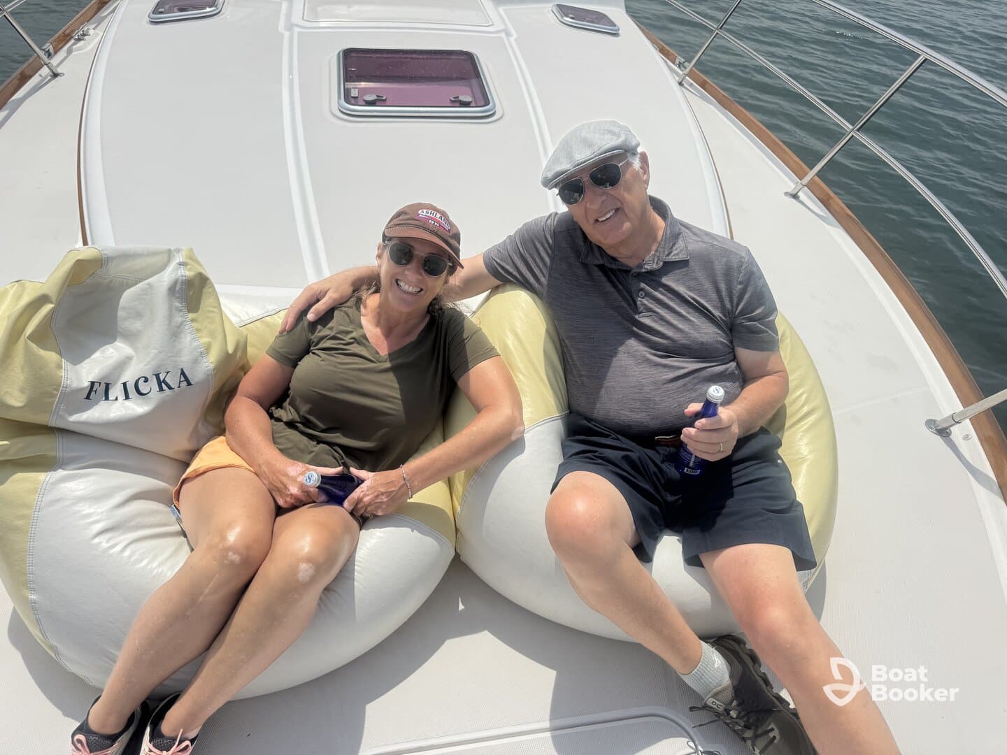 A couple enjoys a relaxing moment on a boat, lounging on bean bags with drinks in hand — perfect for a leisurely day on the water.