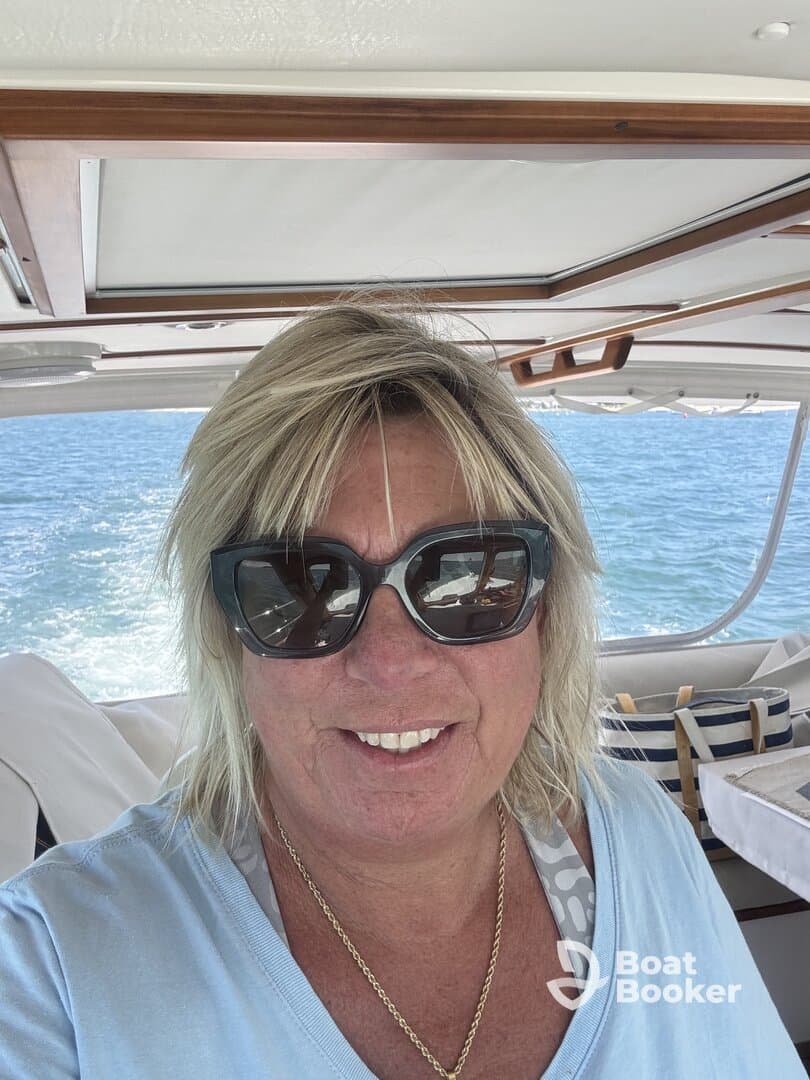 A woman smiles for a selfie inside the helm of a boat, showcasing the cozy cabin atmosphere while enjoying a day on the water.
