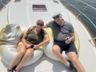 A couple enjoys a relaxing moment on a boat, lounging on bean bags with drinks in hand — perfect for a leisurely day on the water.