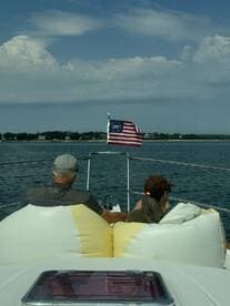 A couple enjoys a relaxing moment on a boat, taking in the scenic views of the water and shoreline. Perfect for romantic getaways or leisurely outings.