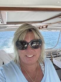 A woman smiles for a selfie inside the helm of a boat, showcasing the cozy cabin atmosphere while enjoying a day on the water.