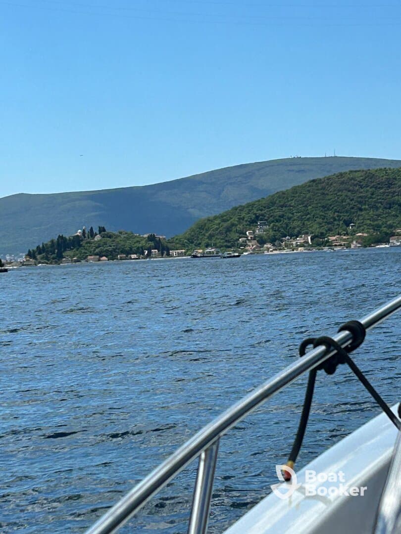 A picturesque view of a serene coastline and lush mountains from a boat, showcasing the beauty of the landscape — perfect for nature lovers and boat enthusiasts.