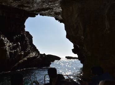 A captivating view from inside a cave, showcasing sparkling water and sunlight filtering through the rock formations — a perfect moment during a scenic boat tour.