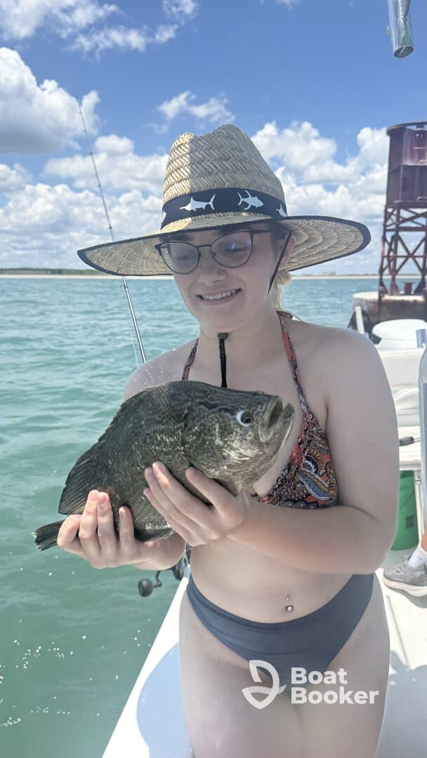 A young girl proudly holds a freshly caught fish while enjoying a day of fishing on the water, showcasing the excitement of wildlife encounters.