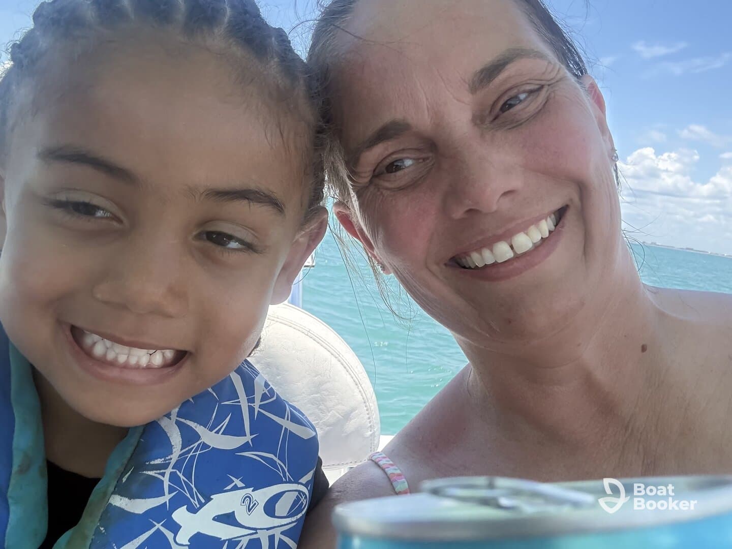 A joyful moment captured between a child and an adult on a boat, showcasing smiles and the beautiful water backdrop — perfect for family outings on the water.