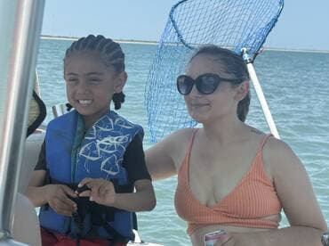 A joyful moment aboard a boat with a child wearing a life jacket and an adult enjoying the day on the water — perfect for family outings and adventures.