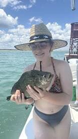A young girl proudly holds a freshly caught fish while enjoying a day of fishing on the water, showcasing the excitement of wildlife encounters.