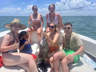 A joyful group celebrates a successful fishing trip on a boat, showcasing their catch and enjoying the sunny day on the water.
