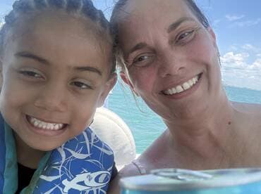 A joyful moment captured between a child and an adult on a boat, showcasing smiles and the beautiful water backdrop — perfect for family outings on the water.