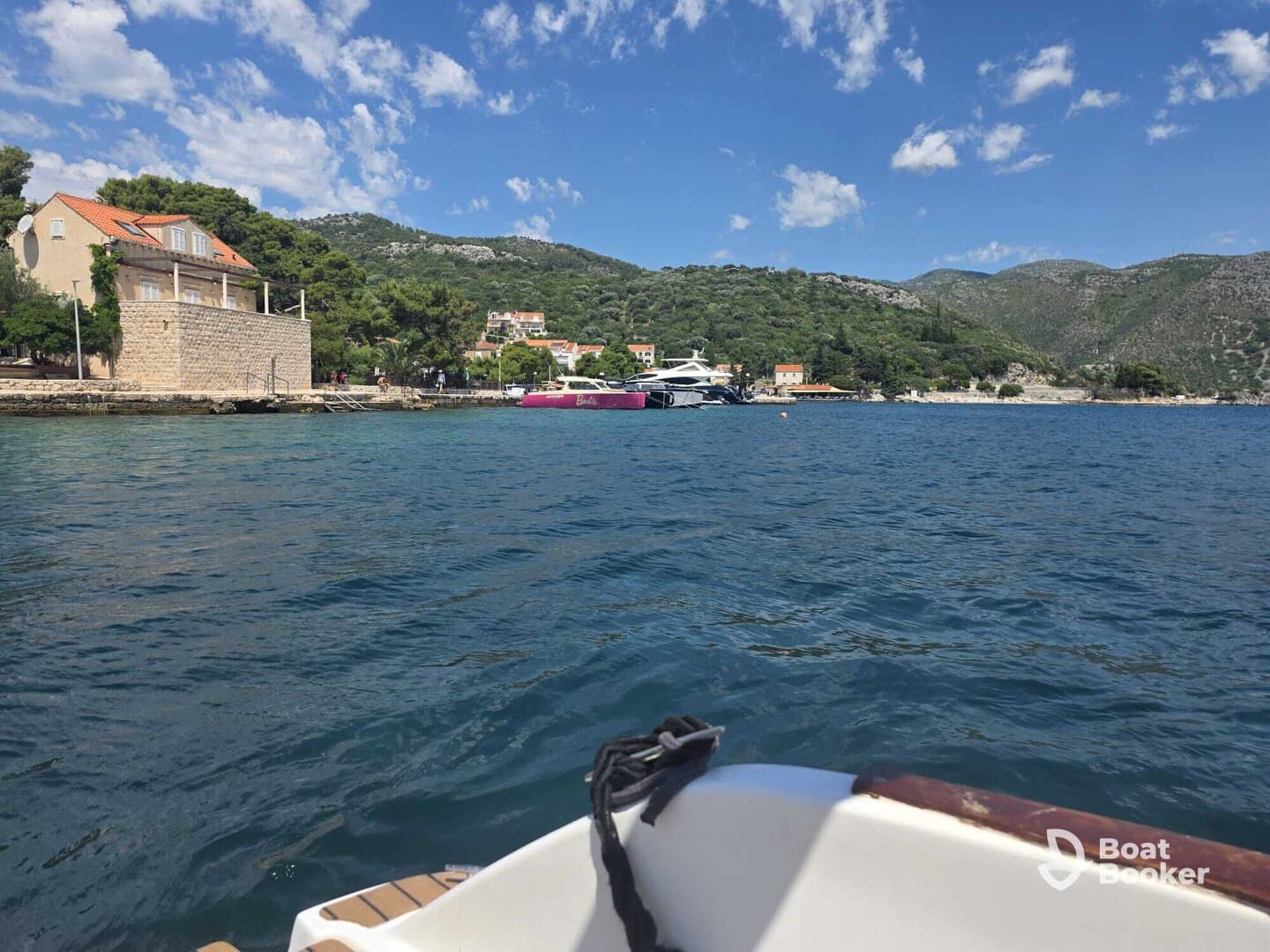 A scenic view of a yacht docked in a picturesque harbor, surrounded by lush greenery and charming coastal architecture.