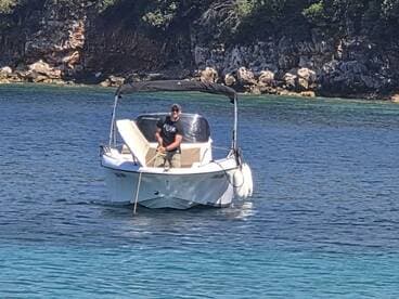 A man enjoys a day on the water, skillfully navigating his boat through crystal-clear waters, perfect for a relaxing boating experience.