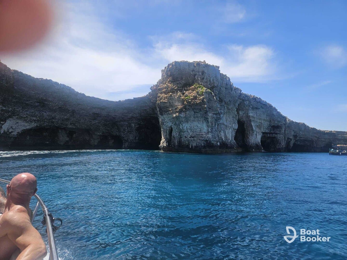 A scenic view of dramatic cliffs and clear blue waters, with a guest enjoying the boat ride — perfect for exploring coastal wonders.