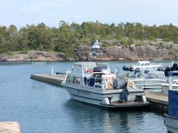 A sleek boat docked at a serene marina, surrounded by lush greenery and rocky shores, perfect for exploring the tranquil waters.