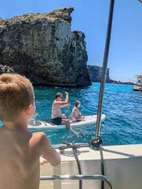 A father and child enjoy paddleboarding in crystal-clear waters, surrounded by stunning rock formations — a perfect family adventure on the water.