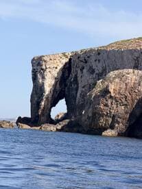 A stunning view of a natural rock formation with an arch, showcasing the beautiful coastline — a perfect highlight for any boating adventure.