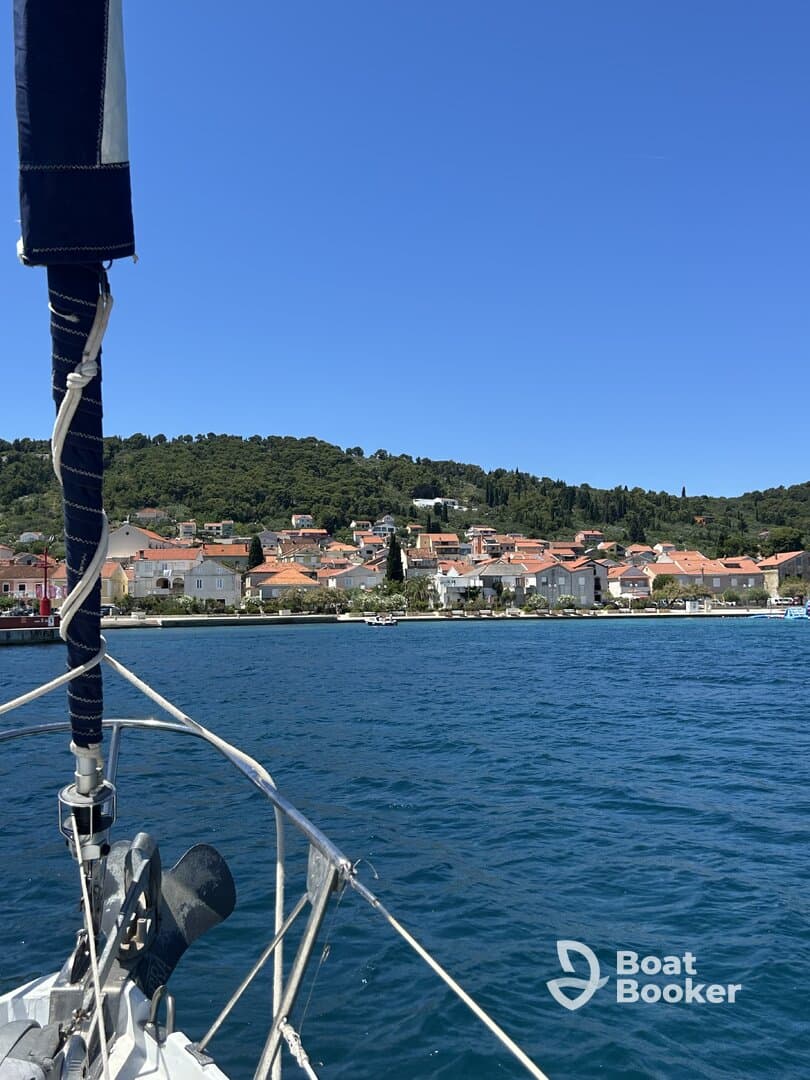 A picturesque view of a charming coastal town from the deck of a sailboat, showcasing the vibrant rooftops and lush greenery along the shoreline — perfect for sailing enthusiasts and travelers exploring beautiful harbors.