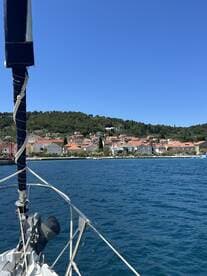 A picturesque view of a charming coastal town from the deck of a sailboat, showcasing the vibrant rooftops and lush greenery along the shoreline — perfect for sailing enthusiasts and travelers exploring beautiful harbors.