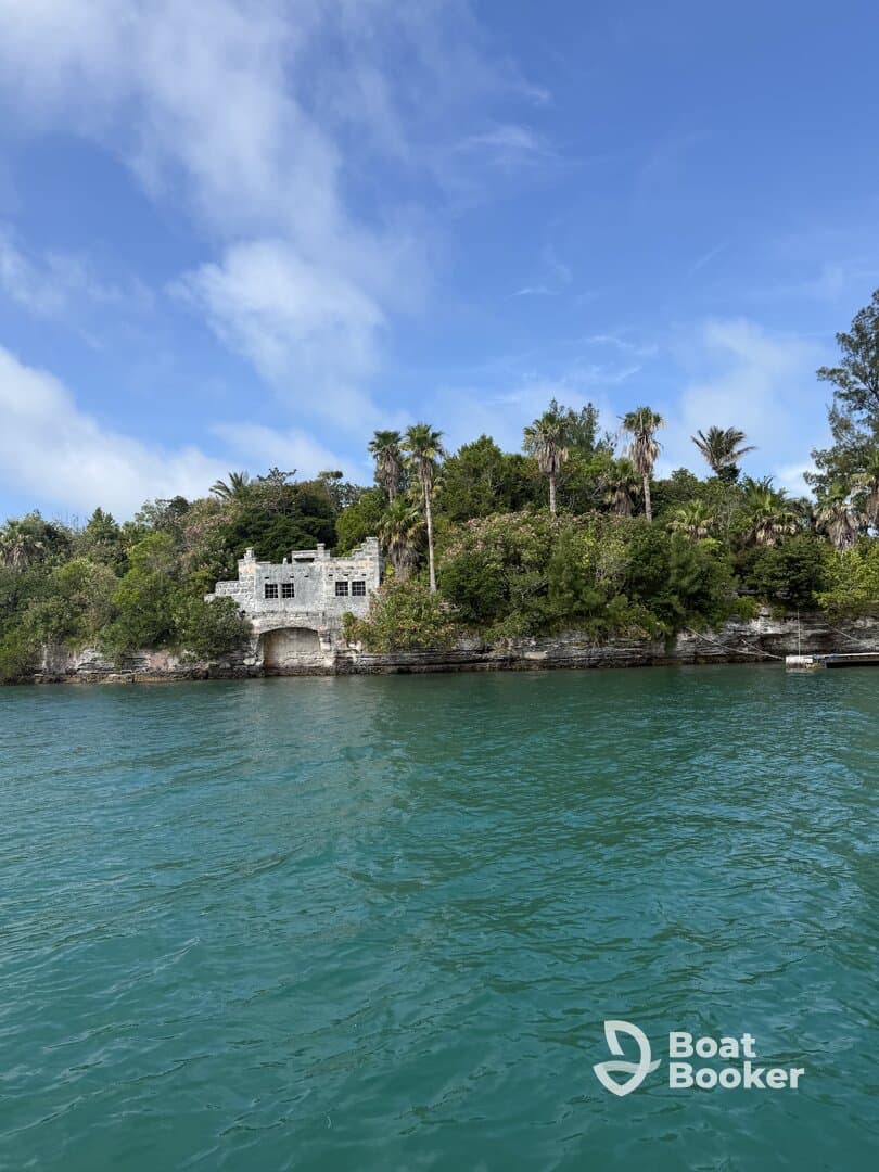 A picturesque view of a historic structure surrounded by lush greenery along the turquoise waters, perfect for exploring scenic landmarks during a boat trip.