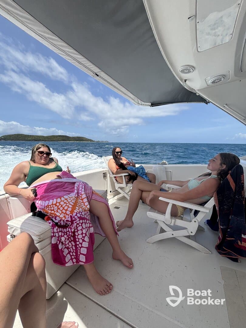 A group of friends relaxes on the deck of a boat, enjoying the sunny weather and beautiful ocean views — perfect for a day of leisure on the water.