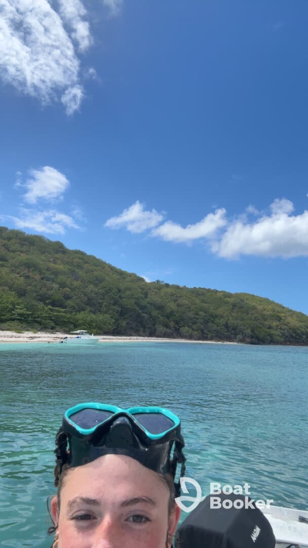 A snorkeler captures a selfie with a beautiful beach and lush greenery in the background, showcasing the perfect spot for underwater adventures.