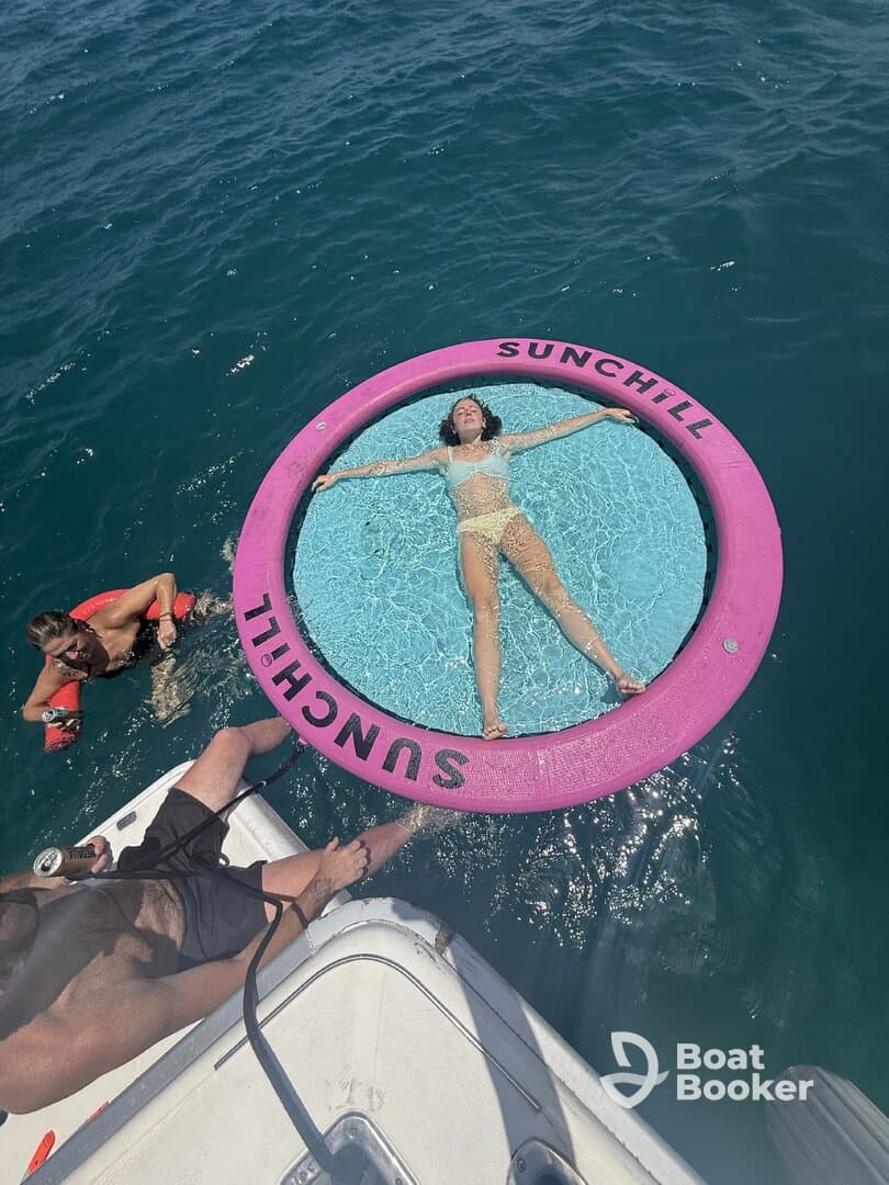 A relaxing scene featuring friends enjoying a sunny day on the water, with one person lounging on a floating mat while others swim nearby — perfect for summer fun and aquatic adventures.