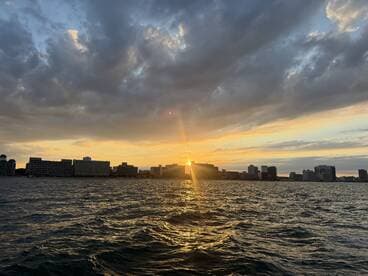 A stunning sunset over the city skyline, reflecting on the water — a perfect backdrop for evening boat cruises.