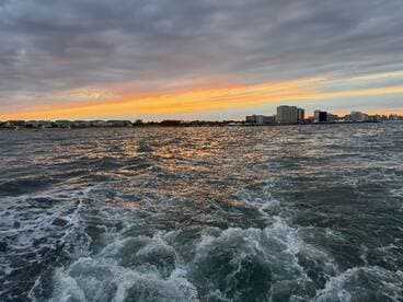 A stunning sunset over the coastline, with gentle waves reflecting the vibrant colors of the sky — a perfect backdrop for evening boat trips.