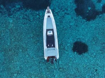 Aerial view of a sleek speedboat anchored over crystal-clear waters, showcasing the stunning underwater landscape — perfect for exploring coastal destinations.