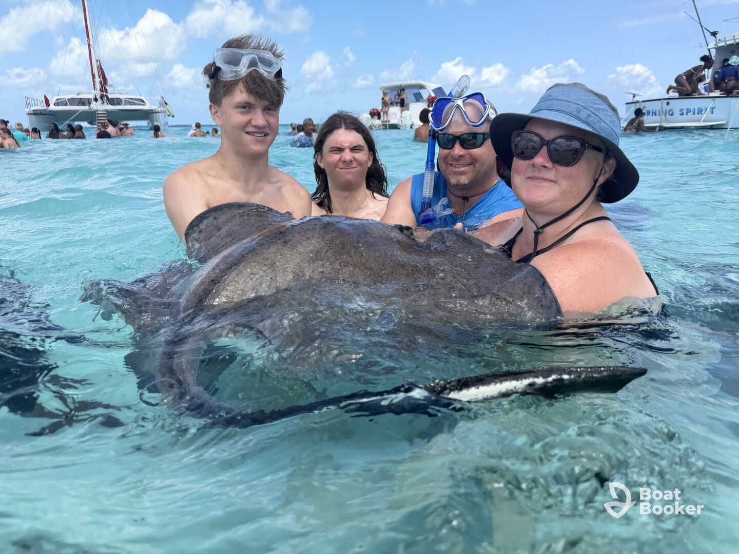 A group of people interact with a stingray in shallow waters, creating an unforgettable wildlife experience in a tropical setting.