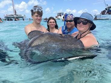 A group of people interact with a stingray in shallow waters, creating an unforgettable wildlife experience in a tropical setting.