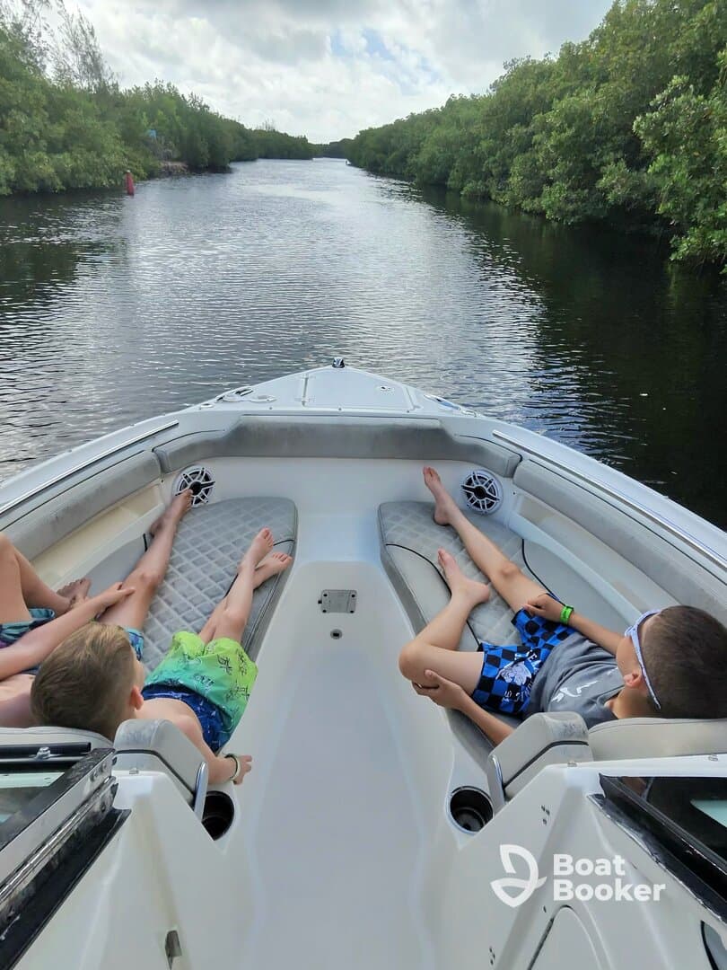 A group of children relaxes on the deck of a boat while cruising through serene mangrove waterways, perfect for family adventures on the water.