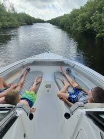 A group of children relaxes on the deck of a boat while cruising through serene mangrove waterways, perfect for family adventures on the water.