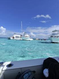 A vibrant scene of multiple boats anchored in crystal-clear turquoise waters, showcasing a lively atmosphere perfect for group outings and water activities.