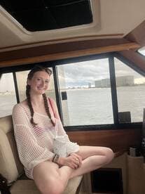 A young woman relaxes in the cabin of a boat, enjoying the scenic view through the large windows — perfect for a comfortable day on the water.