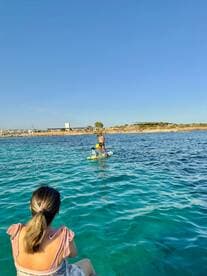A family enjoys paddleboarding in crystal-clear waters, creating unforgettable memories on a sunny beach day.