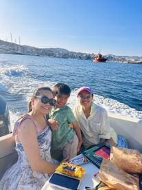 A joyful family enjoys a boat ride, sharing snacks and smiles against a scenic waterfront backdrop — perfect for family outings and adventures on the water.