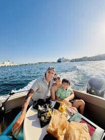 A joyful family enjoys a sunny day on the water, sharing snacks and smiles aboard their boat — a perfect moment for family bonding and fun on the sea.