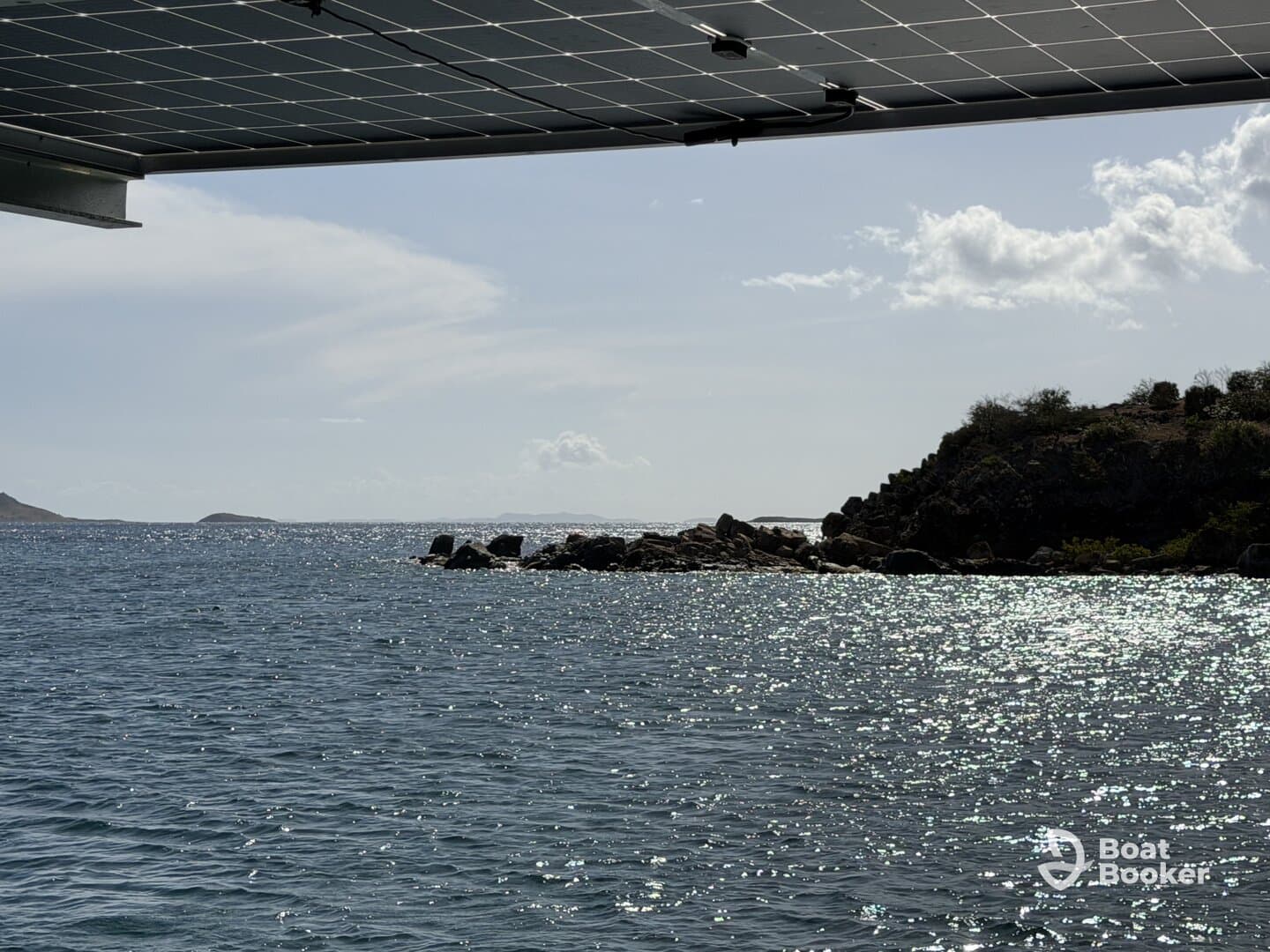 A view of the water and rocky shoreline, with a solar panel partially visible in the frame. The image lacks clarity and detail.