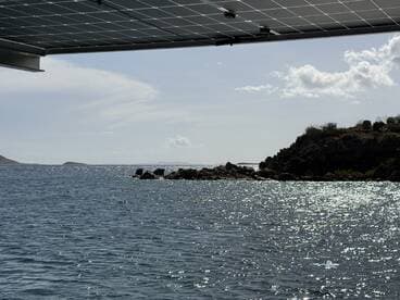 A view of the water and rocky shoreline, with a solar panel partially visible in the frame. The image lacks clarity and detail.