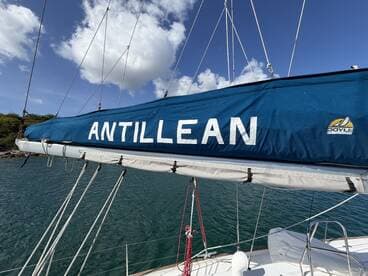 Close-up of the sail cover on the Antillean sailboat, showcasing its vibrant blue color against a backdrop of clear skies and calm waters.