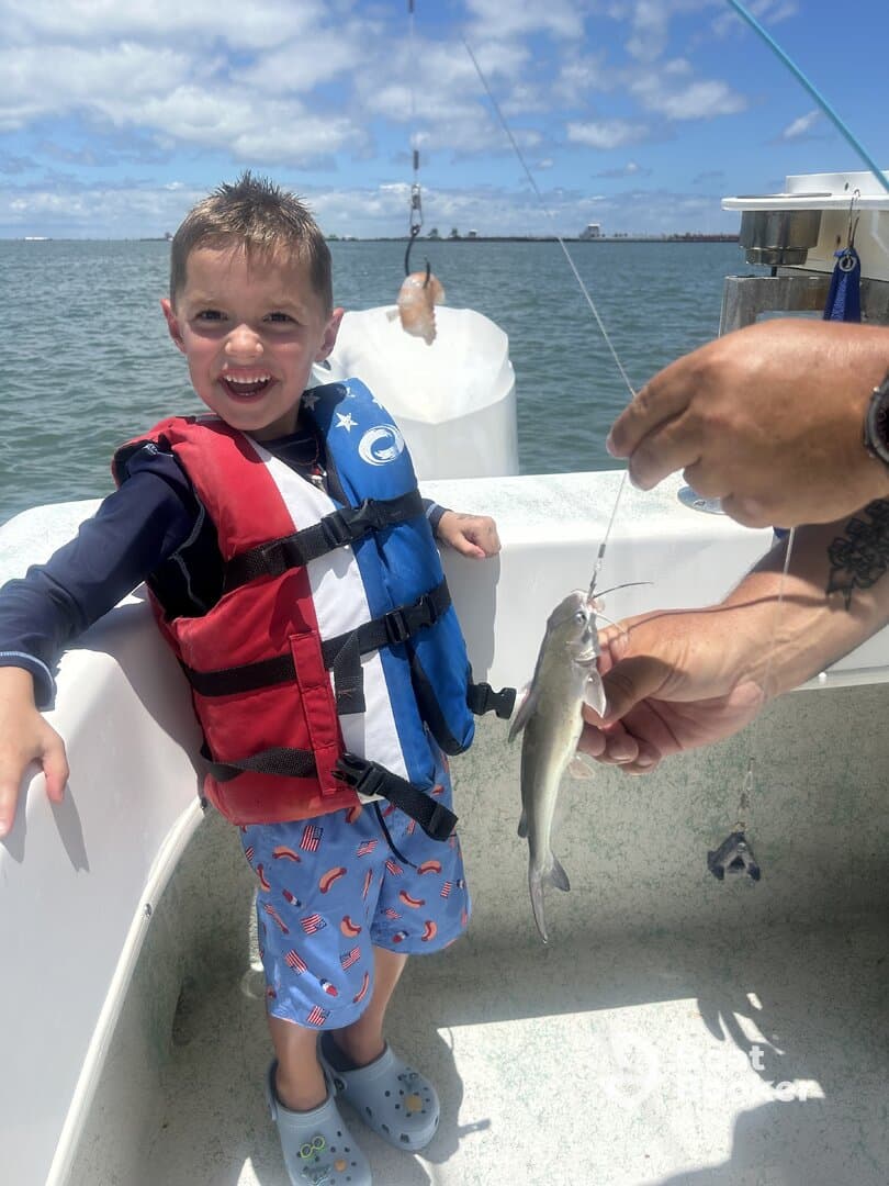 A joyful child proudly displays his catch while fishing on a boat, capturing the excitement of a fun day on the water.