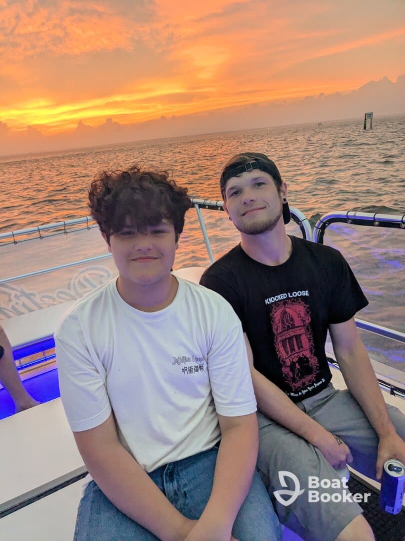 Two friends enjoy a beautiful sunset on a boat, capturing a perfect moment of camaraderie and celebration on the water.