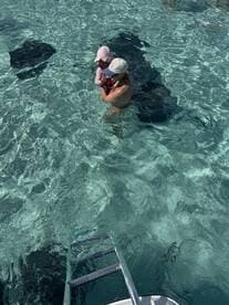 A child and an adult enjoy a close encounter with stingrays in crystal-clear waters, creating a memorable wildlife experience.