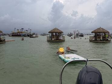 Guests enjoy a lively sandbar stop with various boats and activities in the background, perfect for a fun day on the water.
