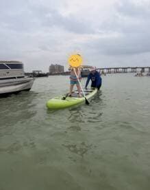 A child enjoys paddleboarding with an adult in shallow waters, showcasing a fun and engaging on-water activity perfect for family outings.